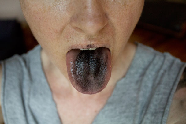 shot of Lambert's tongue while applying the charcoal to her body for performance for a permeable body and installtion by Carolyn Lambert